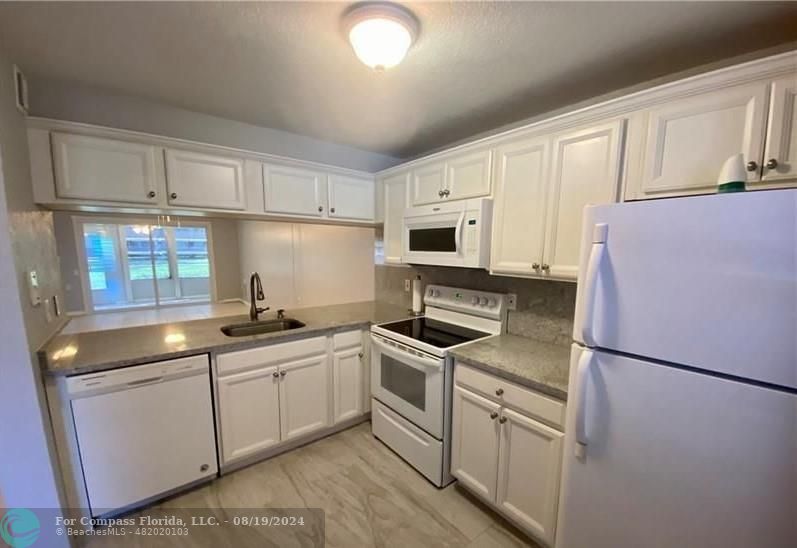 a kitchen with white cabinets sink and white appliances