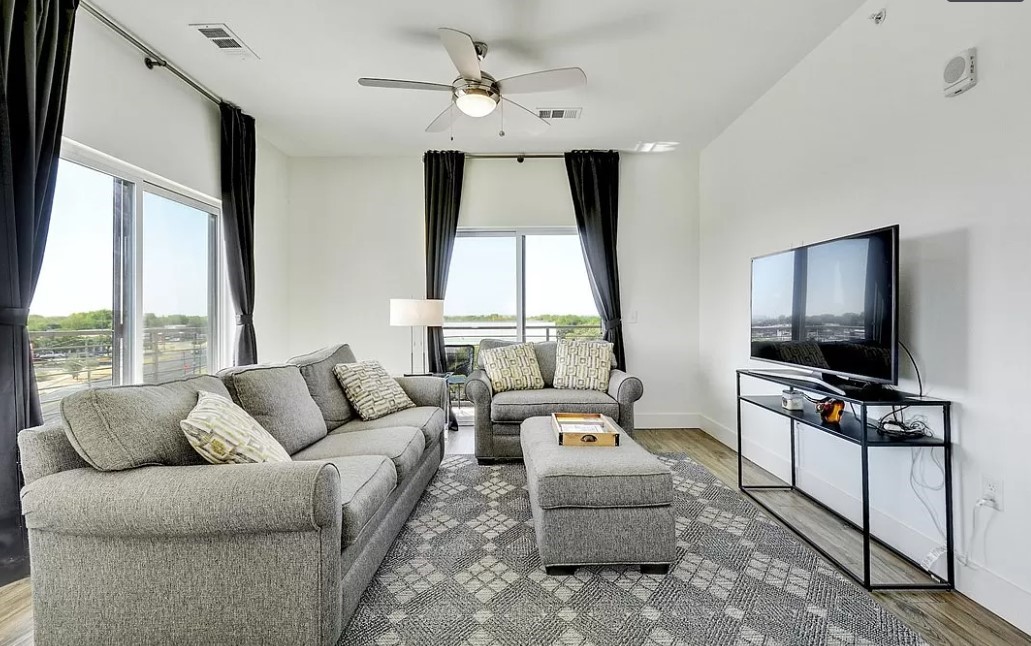 a living room with furniture a flat screen tv and a large window