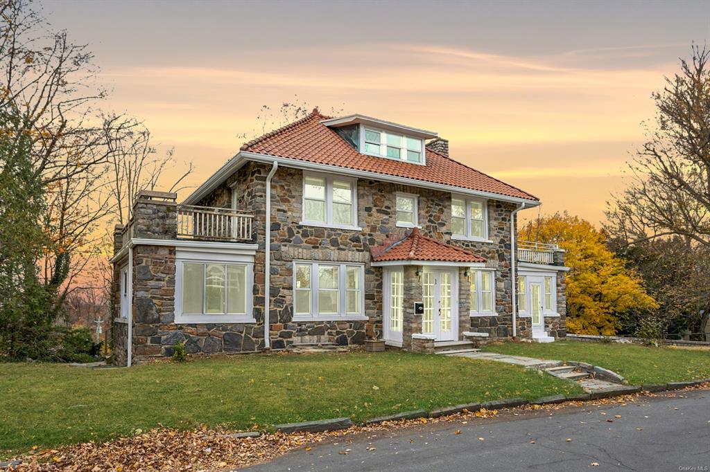 Photo enhanced view of front of this charming Mediterranean home featuring two balconies and a yard