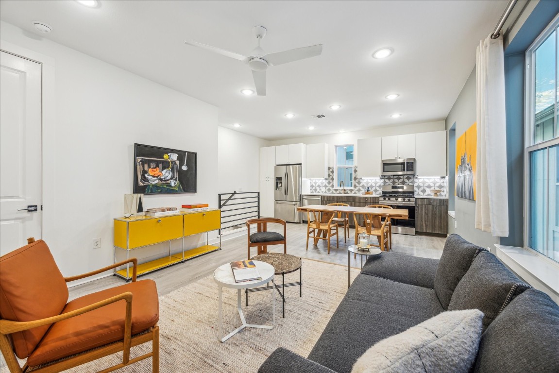 a living room with furniture kitchen view and a chandelier