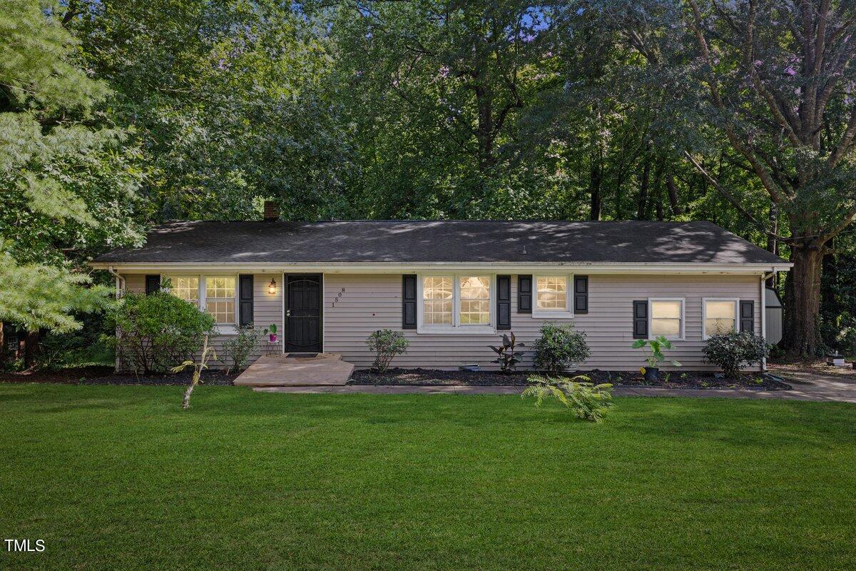 a front view of a house with a garden and trees