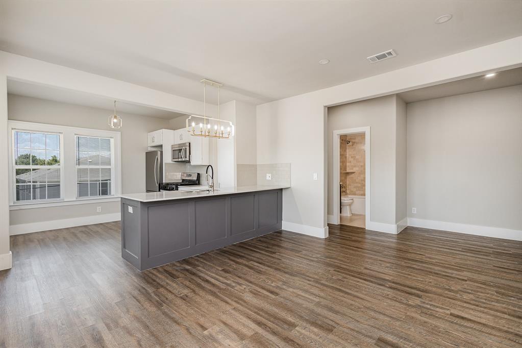 a view of kitchen and empty room with wooden floor