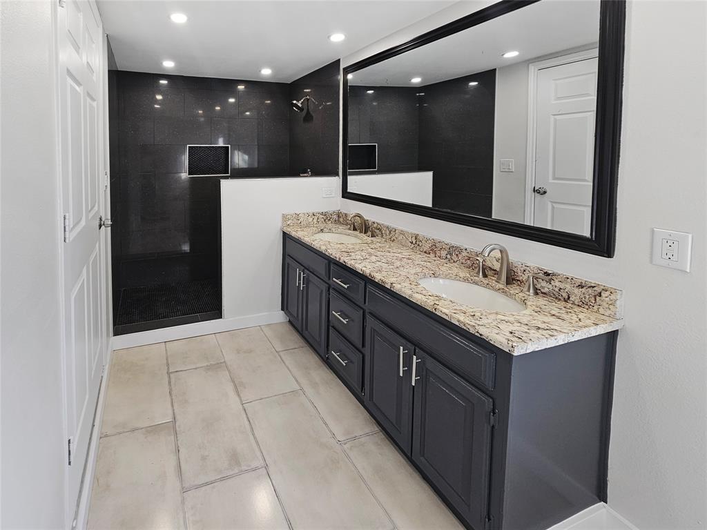 a bathroom with a granite countertop sink a large mirror and shower