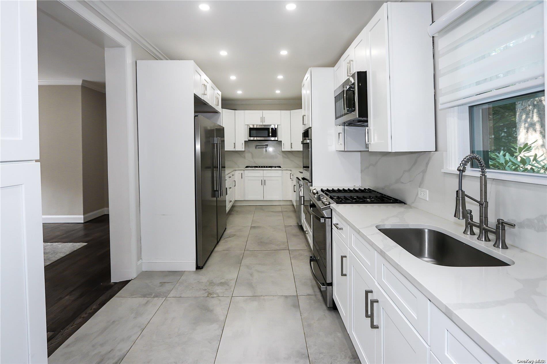 a kitchen with a sink a counter top space stainless steel appliances and cabinets