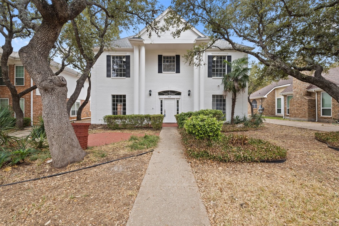 a front view of a house with a yard and trees