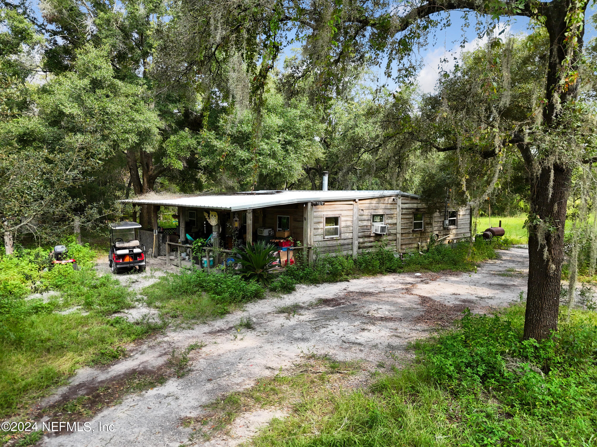 a view of a house with a small yard and large trees