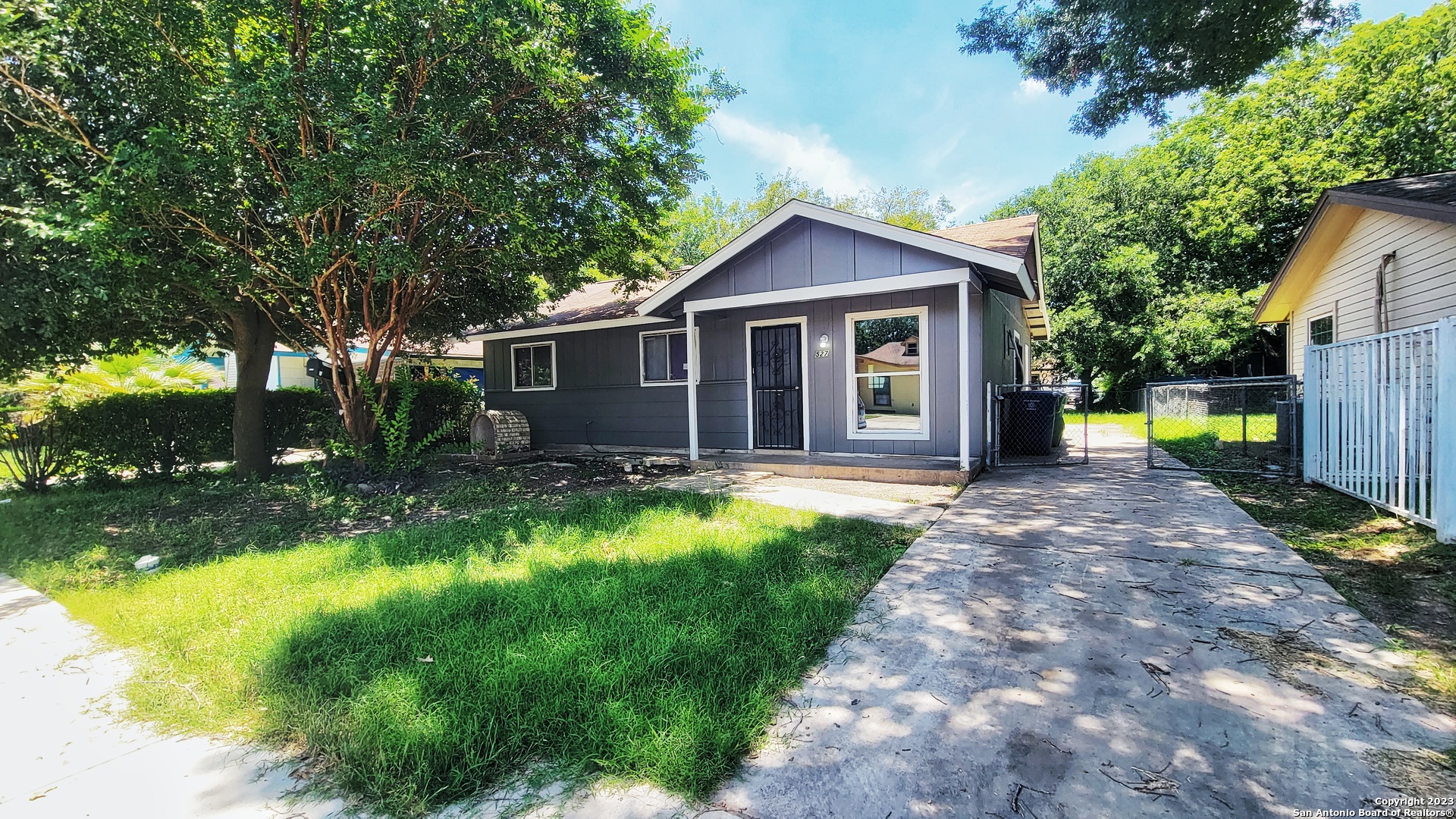 a view of a house with a yard plants and large tree