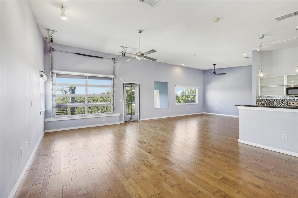 a view of an empty room with window and wooden floor