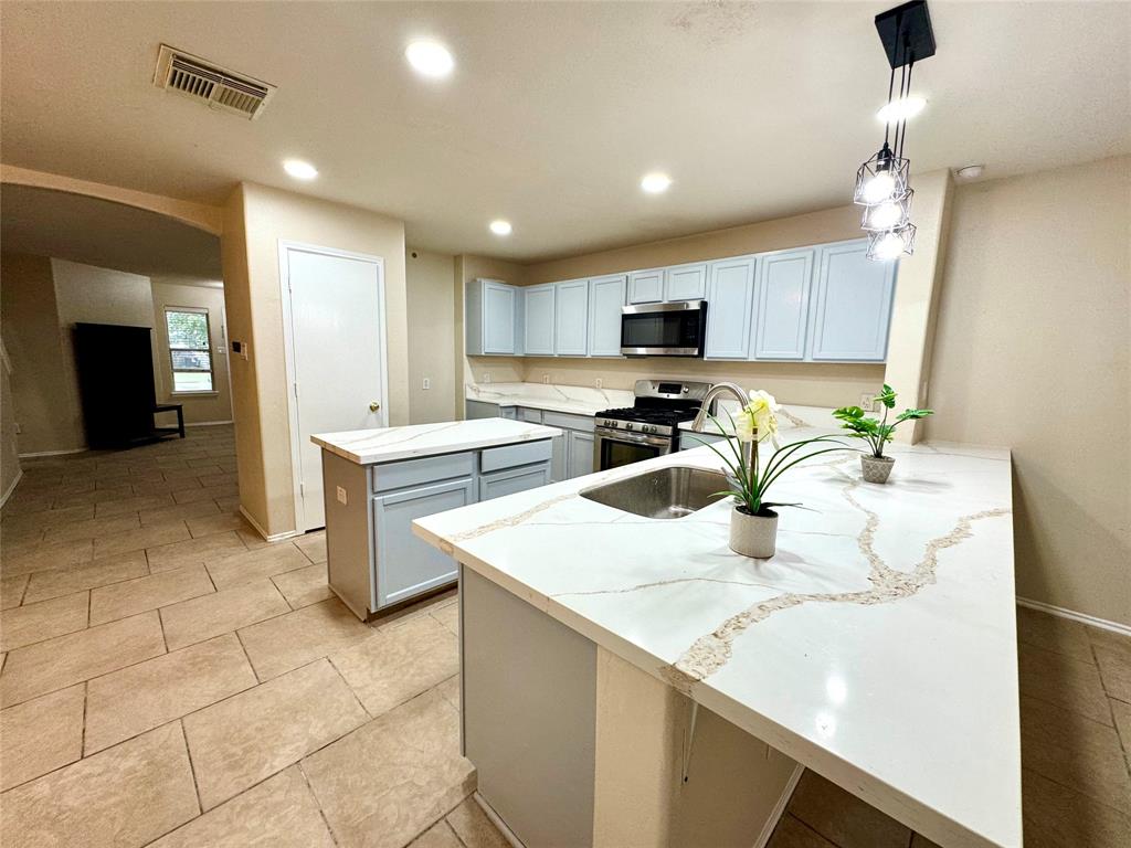 a kitchen with a sink a stove top oven and cabinetry