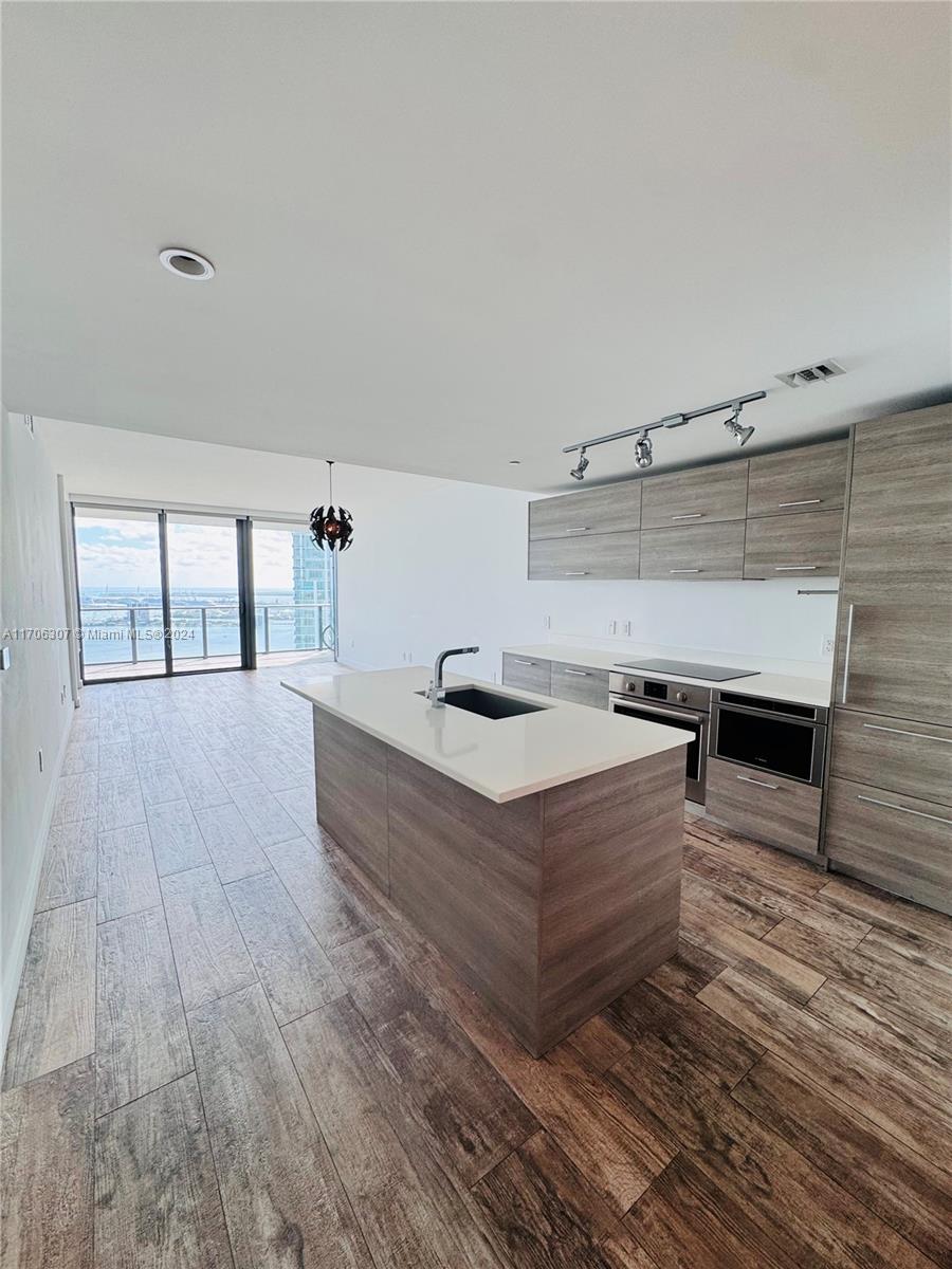 a living room with hard wood floors and a kitchen