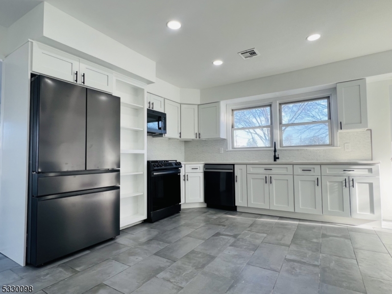 a kitchen with granite countertop a refrigerator and a stove top oven