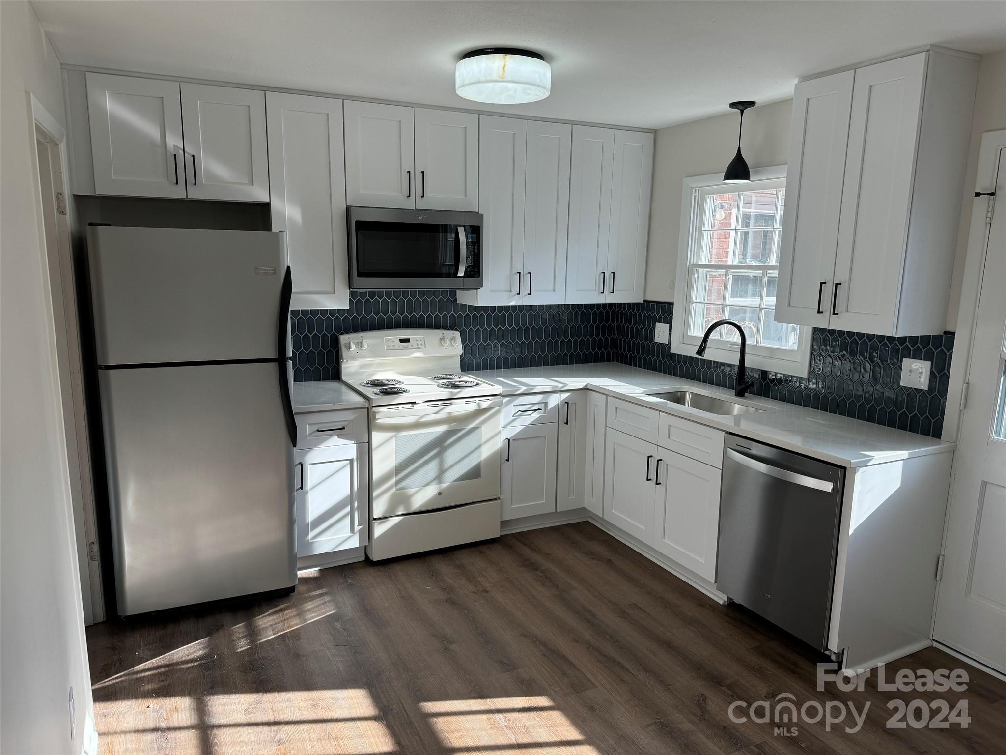 a white kitchen with sink a microwave and cabinets