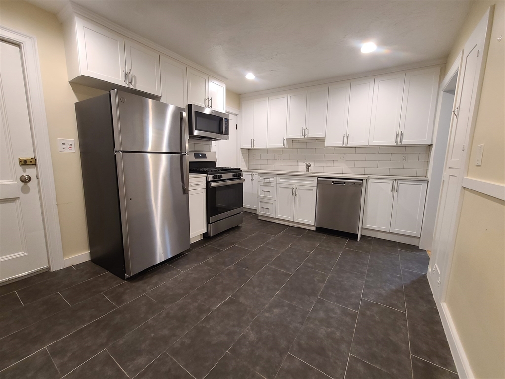 a kitchen with granite countertop a refrigerator and a stove top oven