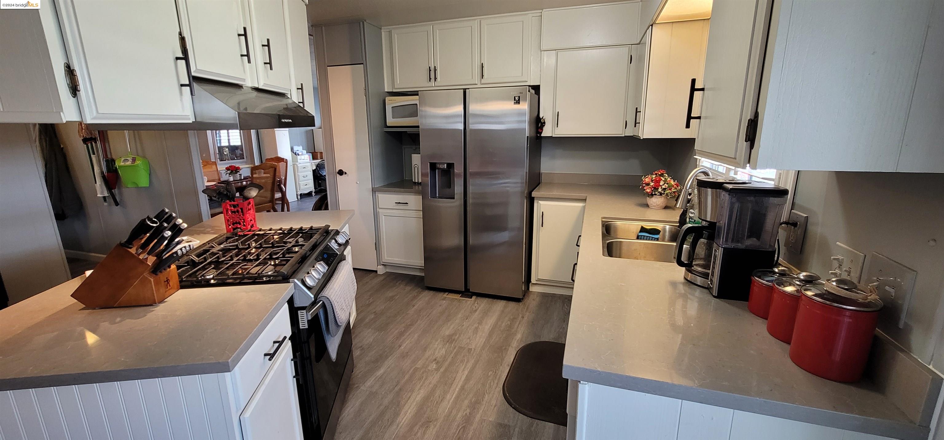 a kitchen with refrigerator a stove and wooden floor