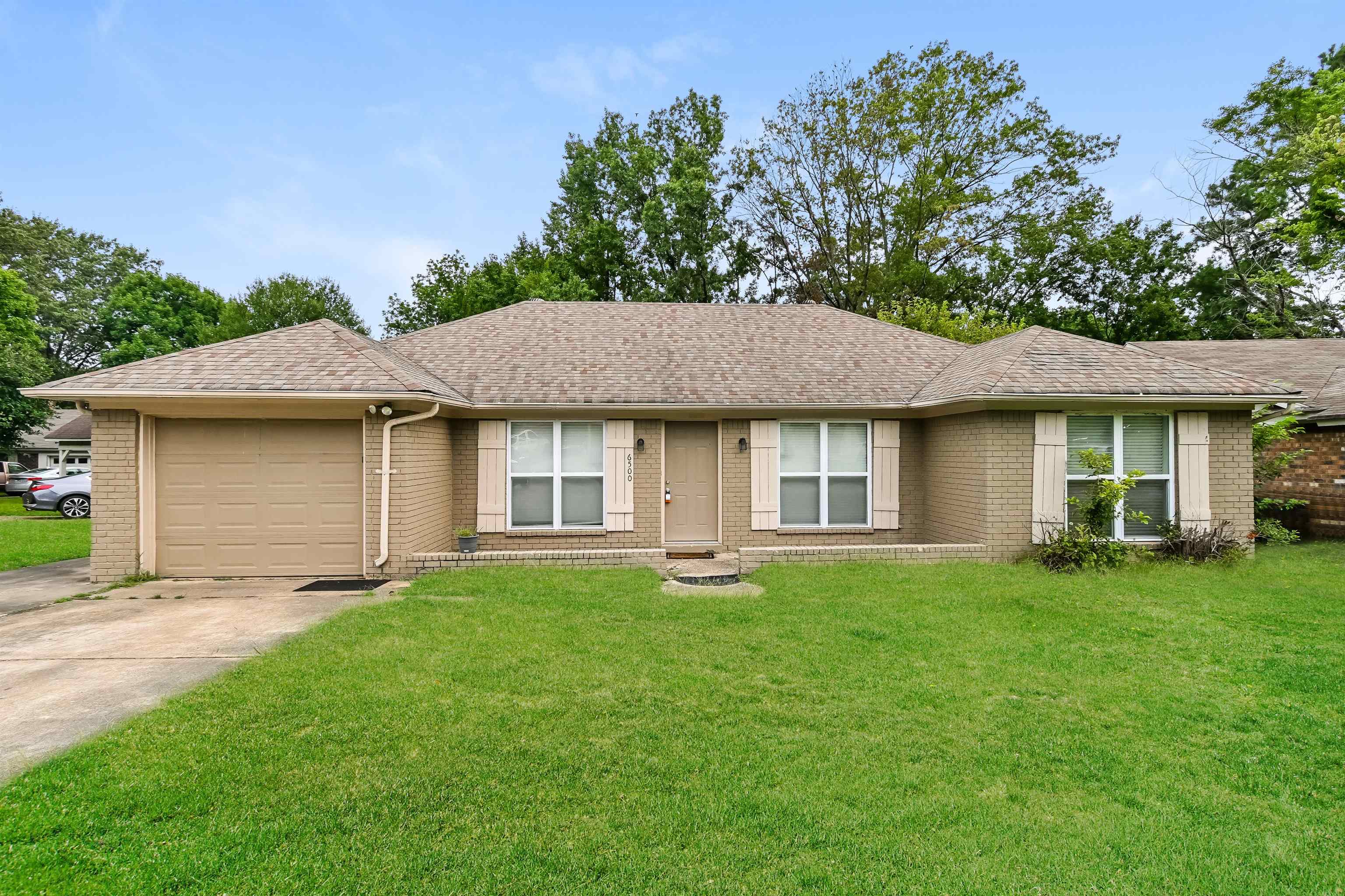 a front view of a house with a garden and yard