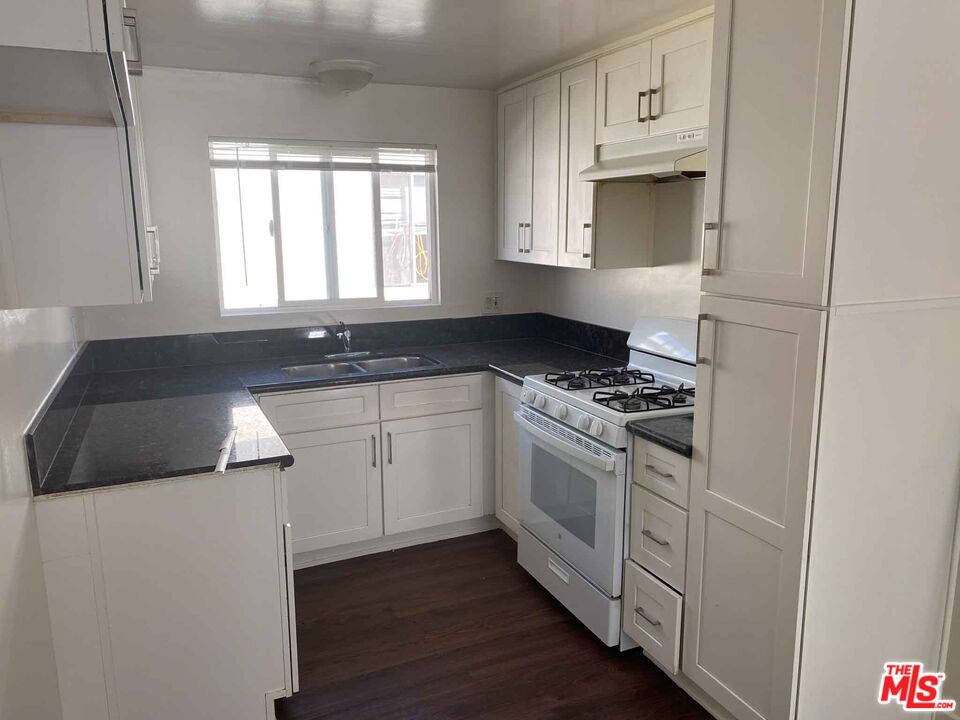 a kitchen with granite countertop white cabinets and white appliances