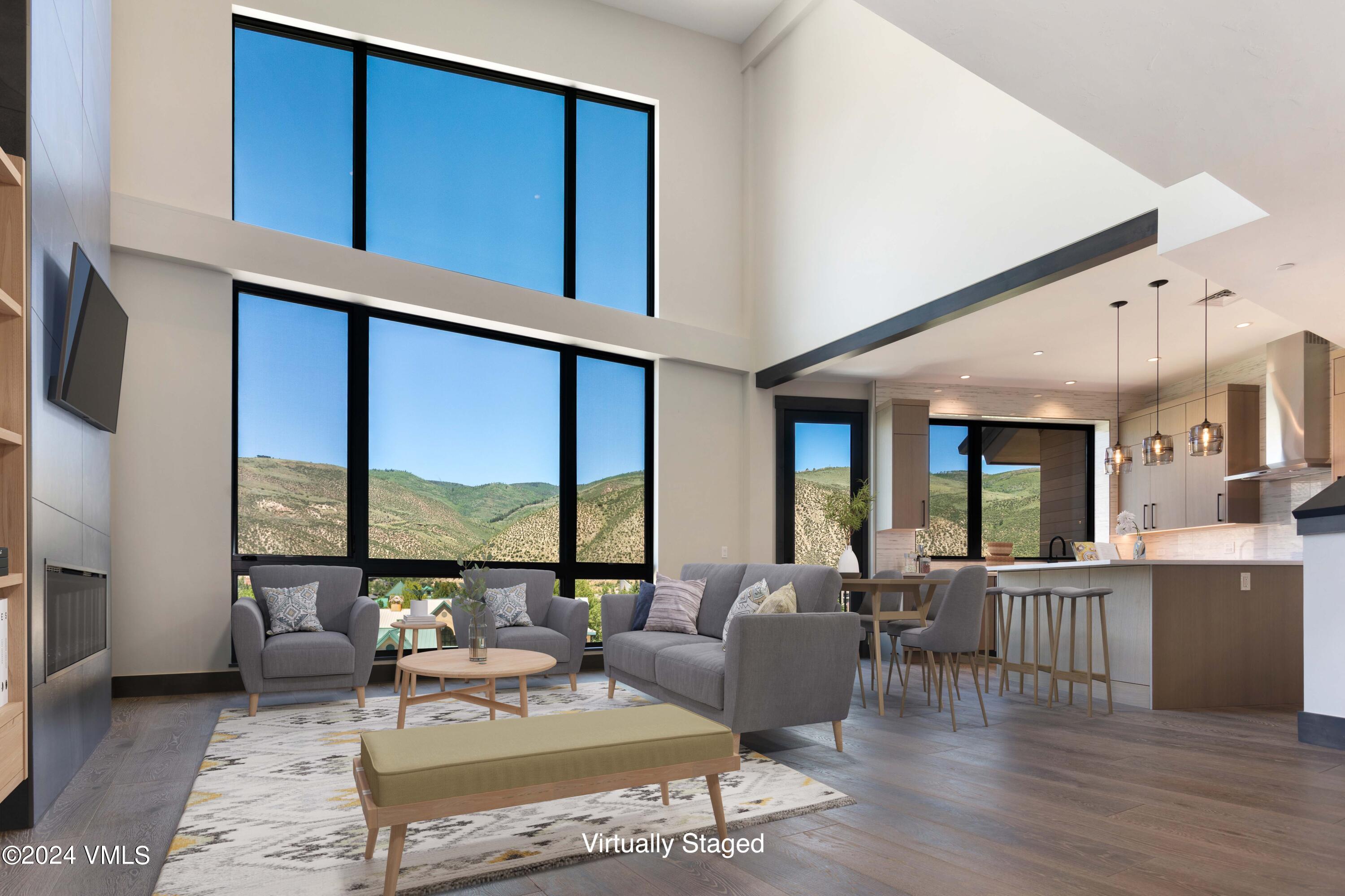 a living room with furniture large windows and wooden floor