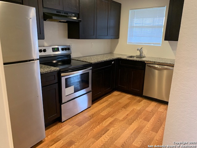 a kitchen with granite countertop a refrigerator stove and sink