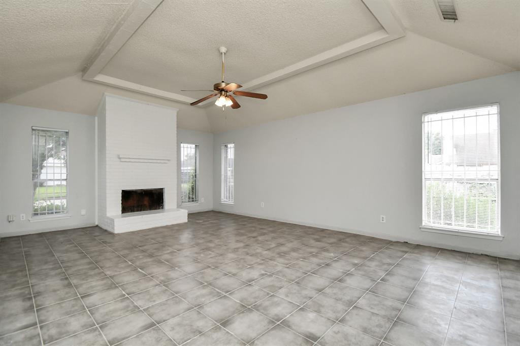 an empty room with windows and fireplace