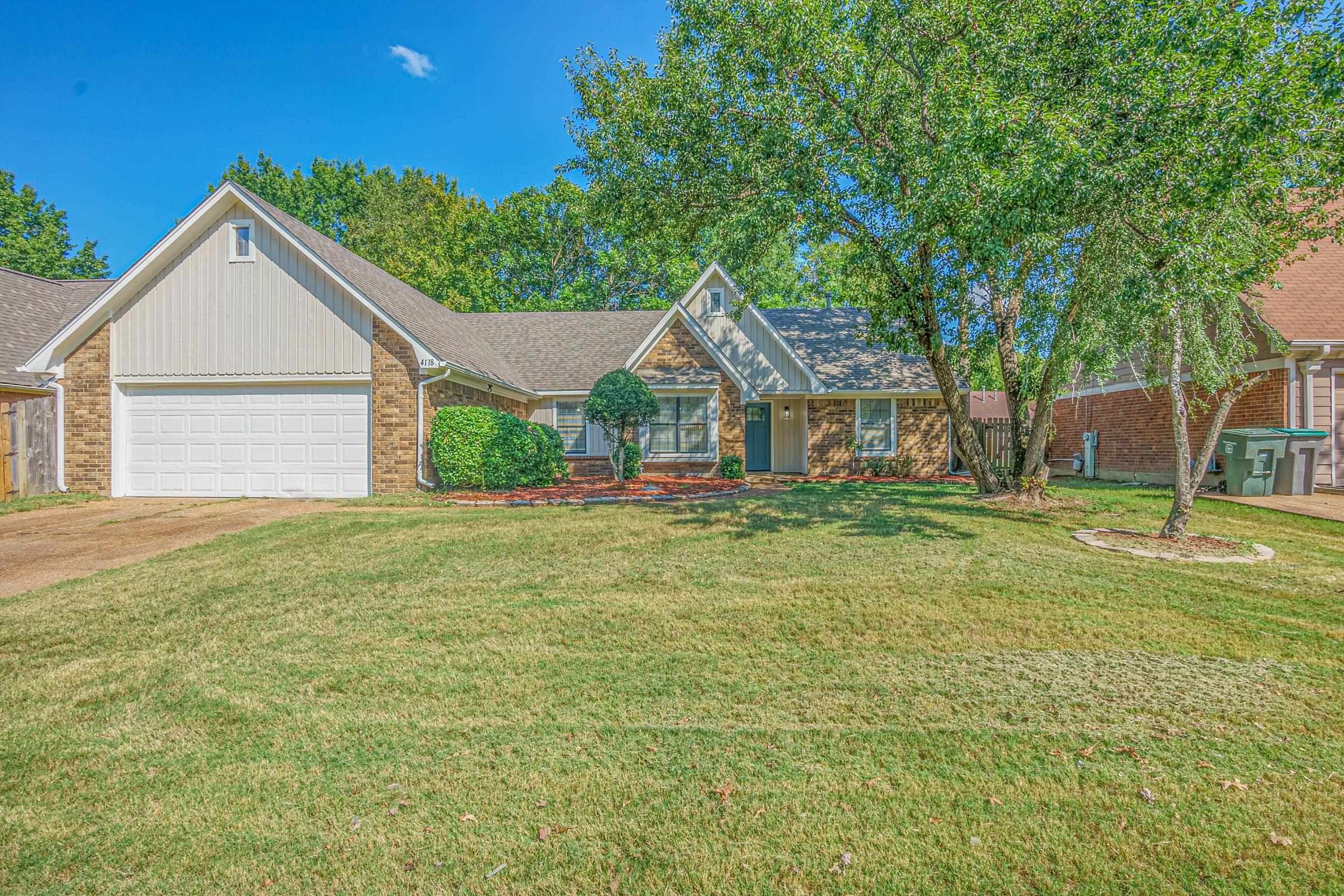 View of front of property featuring a front yard and a garage