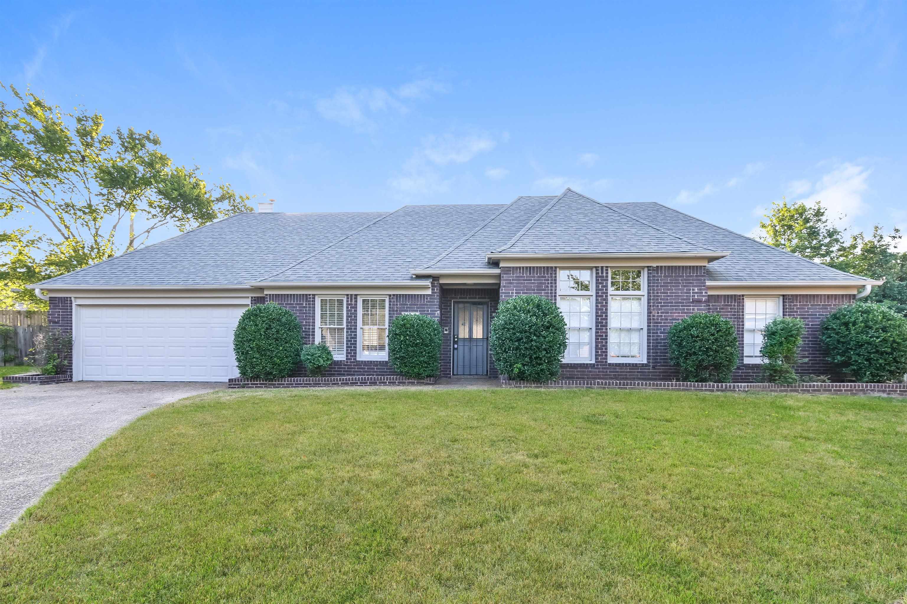 Ranch-style house featuring a garage and a front lawn