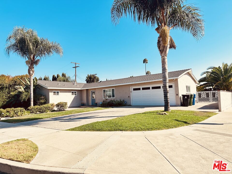 a front view of a house with a garden and palm trees