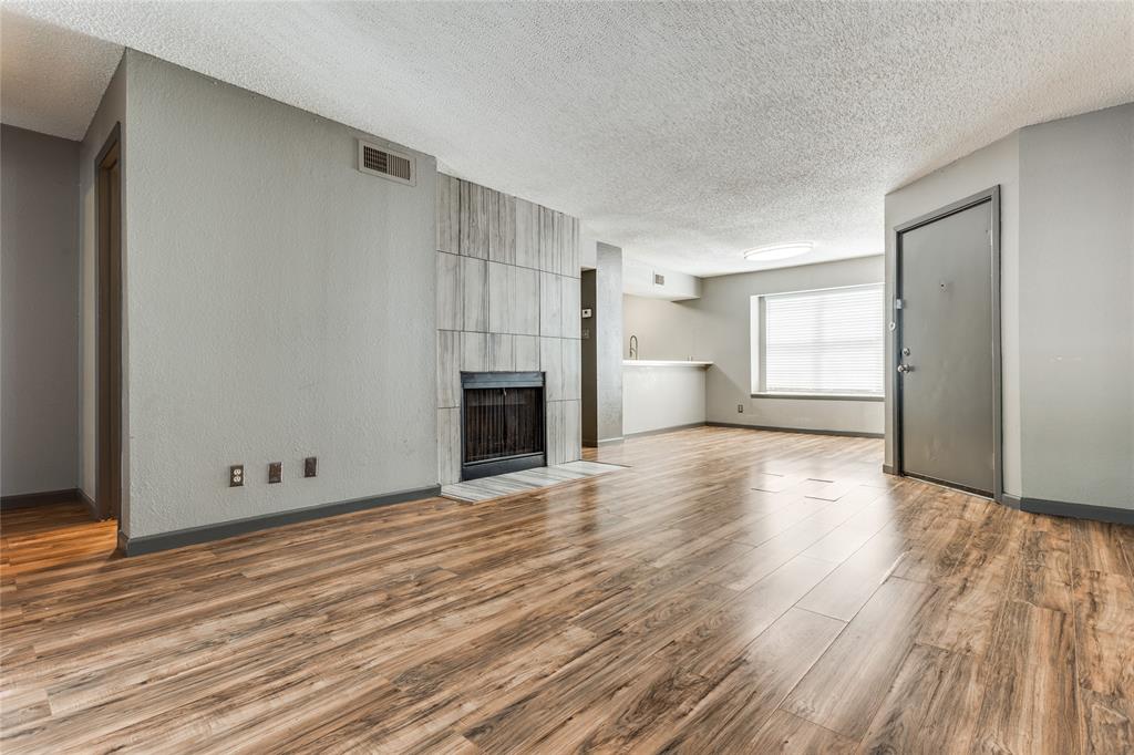 an empty room with wooden floor fireplace and windows