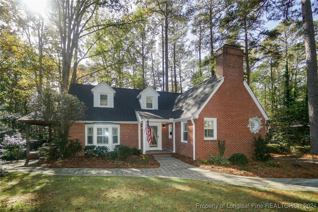 a view of a brick house next to a yard with large trees