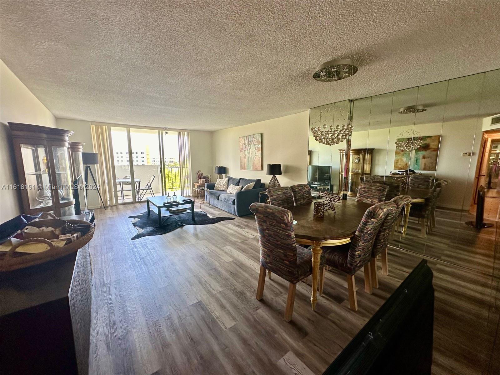 a living room with furniture a large window and wooden floor