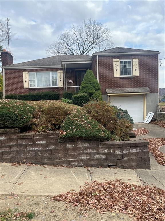 a front view of a house with a yard and a tree