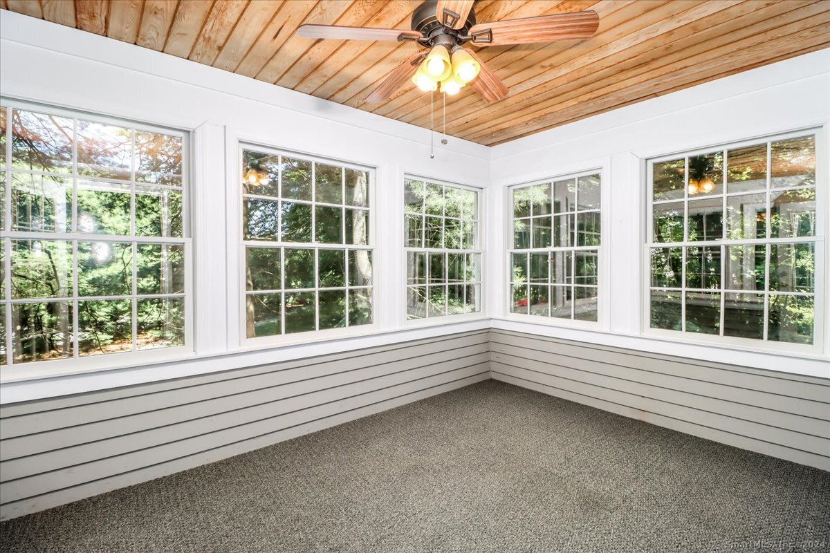 3 season sunroom with Anderson Windows, carpet and ceiling fan. This view looks at view to side and back. Just trees.