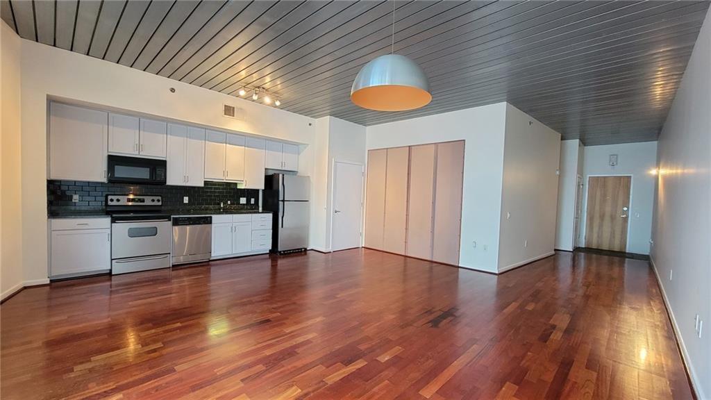 a view of a kitchen with wooden floor and electronic appliances