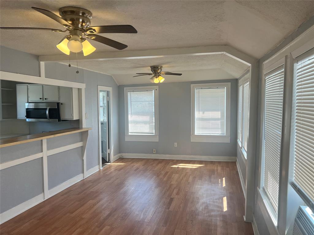 a view of empty room with wooden floor and fan