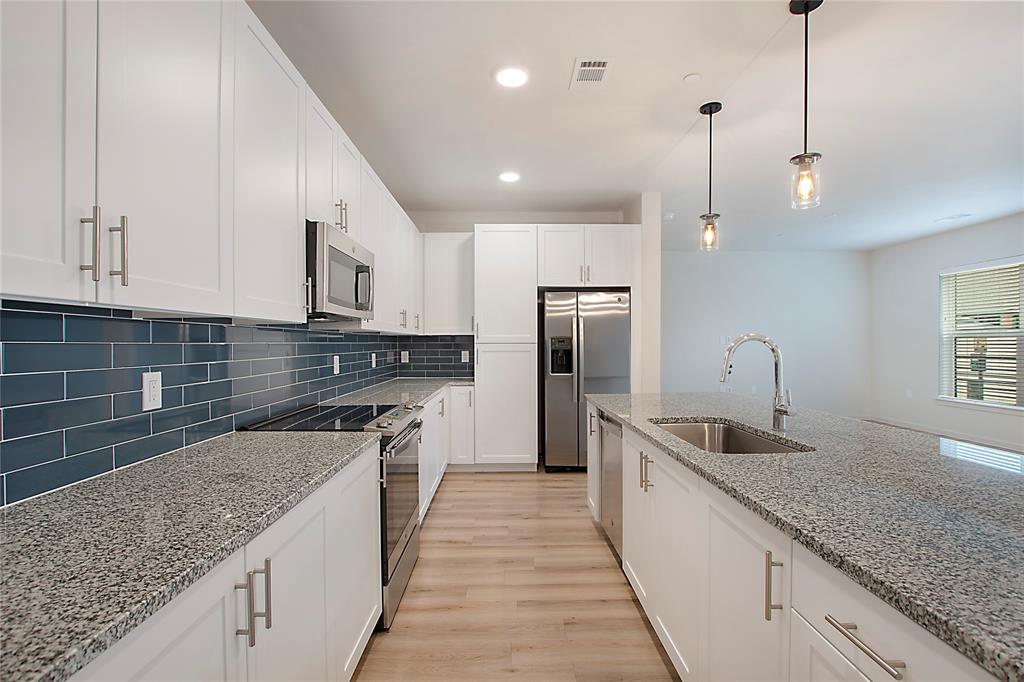 a kitchen with stainless steel appliances granite countertop a sink a stove and a wooden cabinets