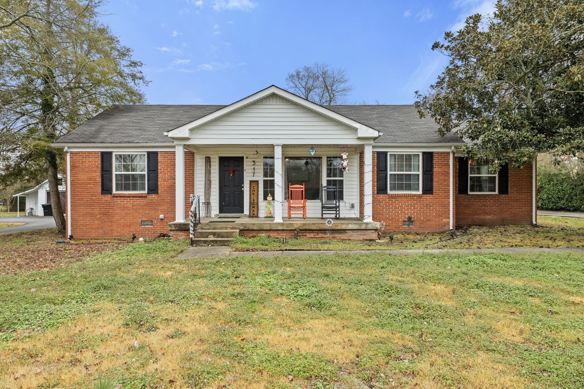 a view of a house with a yard and large tree