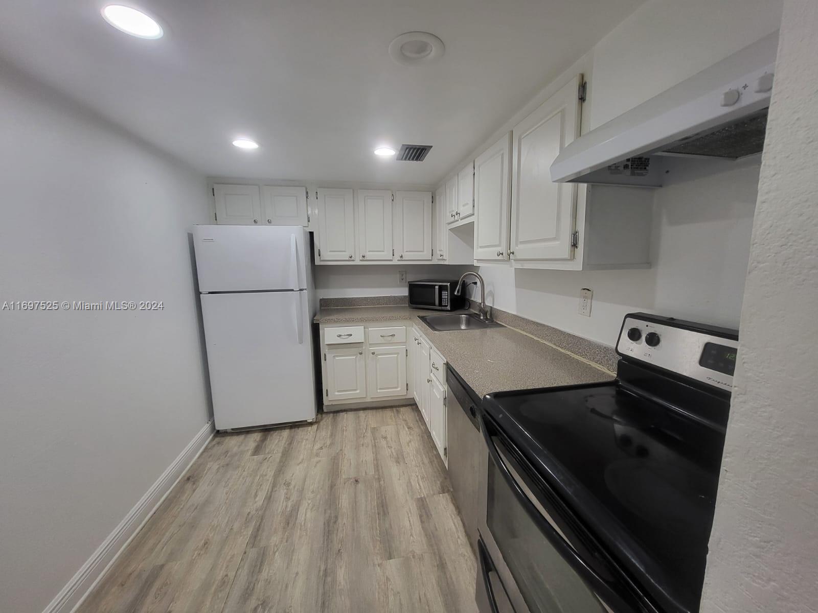 a kitchen with a refrigerator a stove and white cabinets