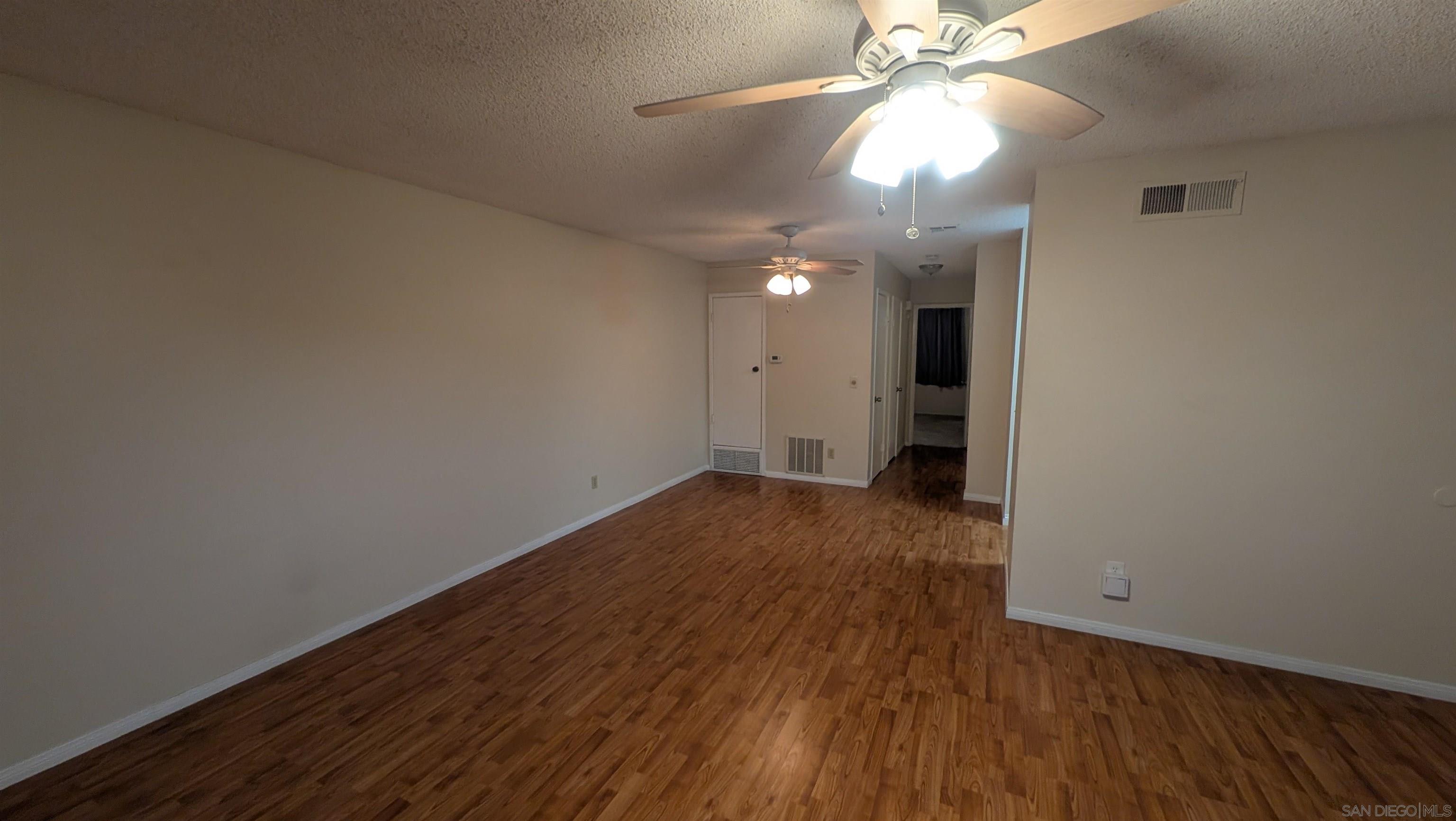 a view of a room with wooden floor and a ceiling fan