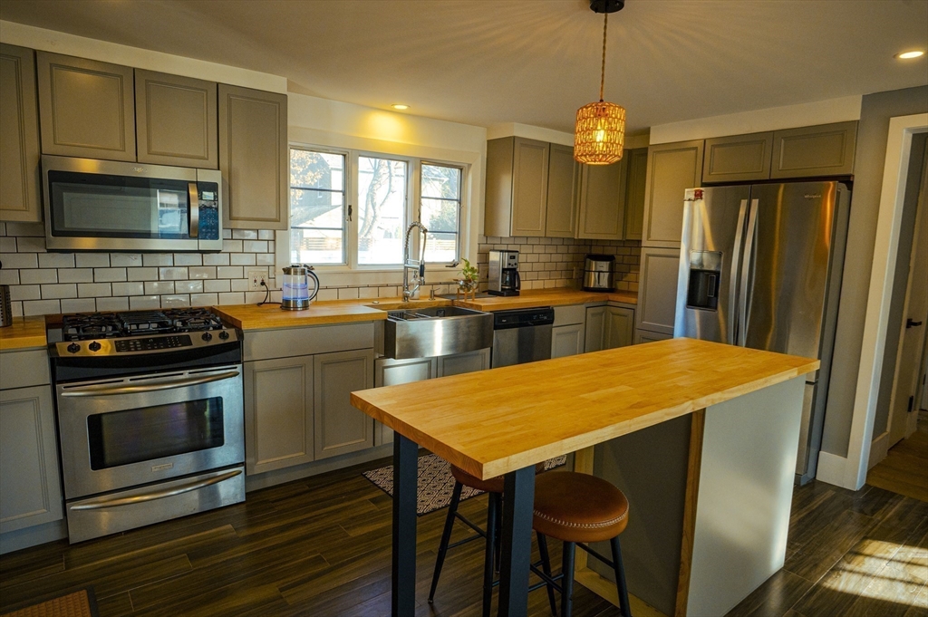 a kitchen with stainless steel appliances granite countertop a stove a sink dishwasher a refrigerator a stove and a dining table with wooden floor