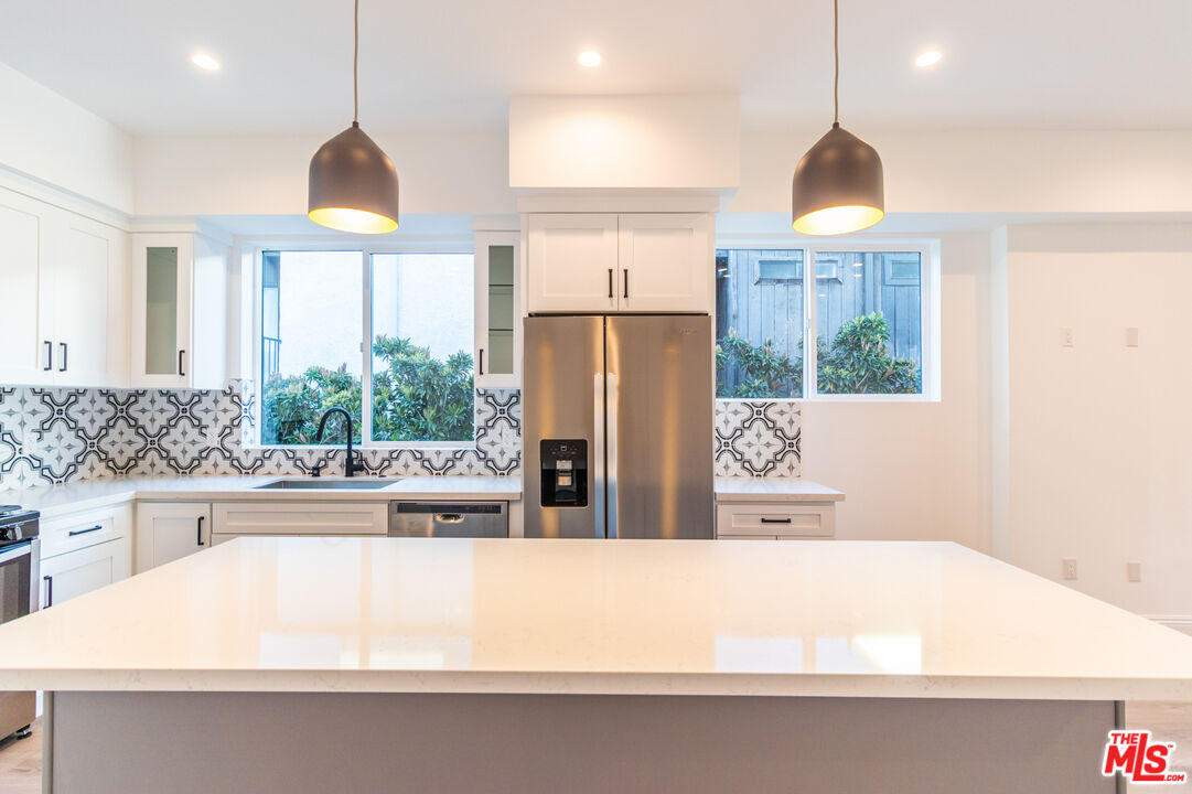 a kitchen with kitchen island a large counter top space a sink stainless steel appliances and cabinets