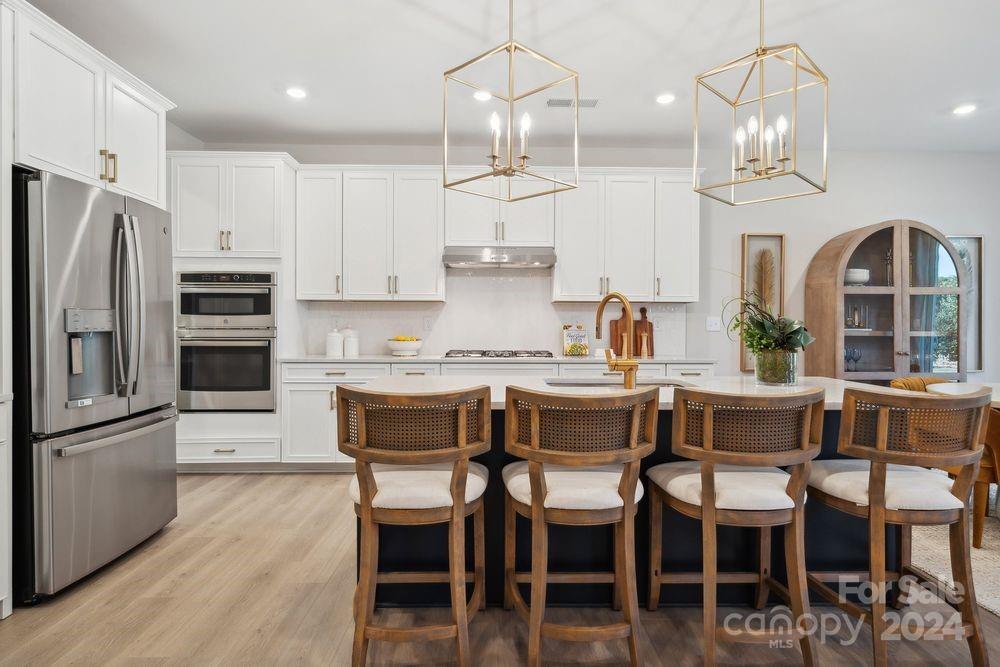 a kitchen with granite countertop a table chairs stove and refrigerator