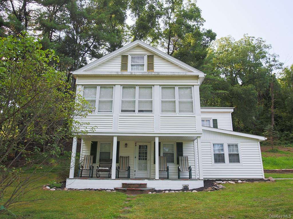 a view of a white house with a small yard plants and large tree