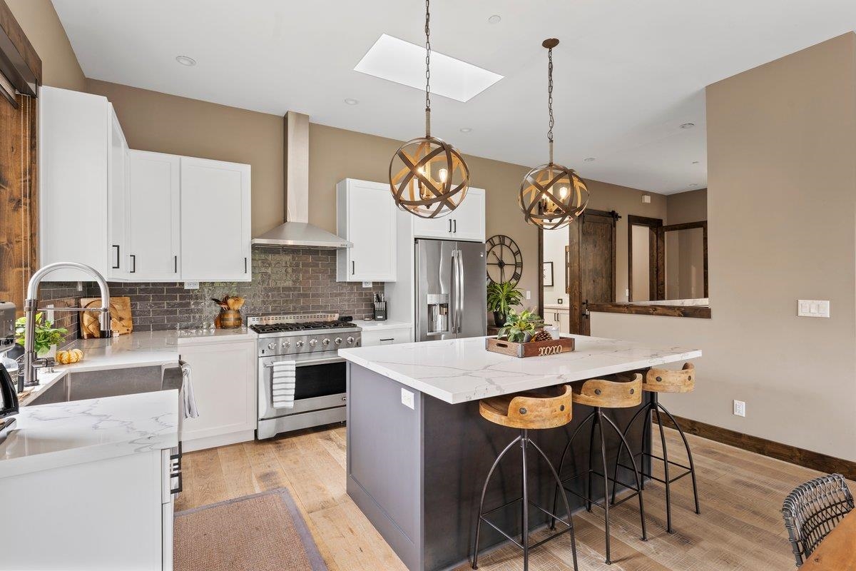 a kitchen with kitchen island granite countertop a stove a sink a center island and chairs