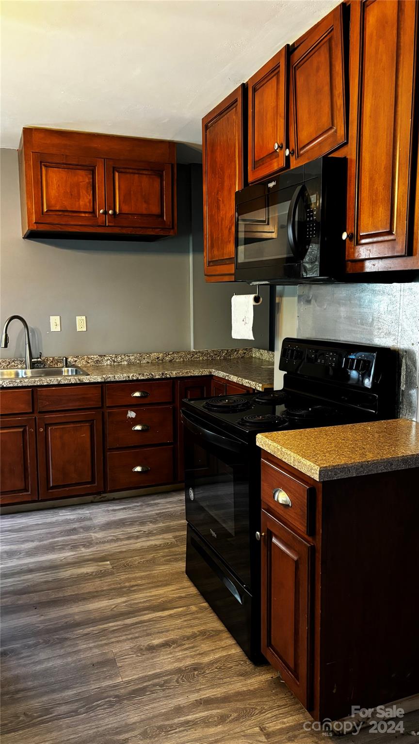 a kitchen with stainless steel appliances granite countertop a stove a sink dishwasher and cabinets with wooden floor