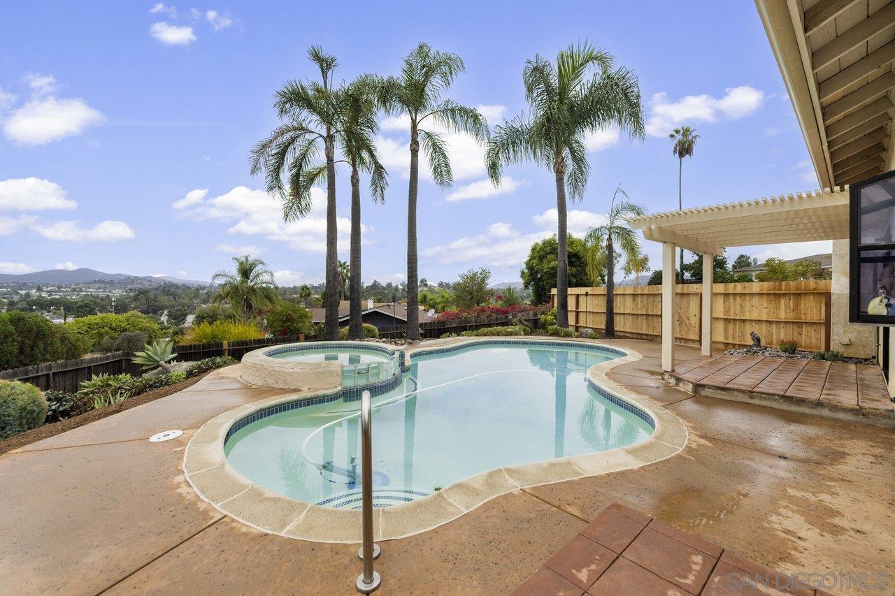 a view of a swimming pool with a lawn chairs under palm trees