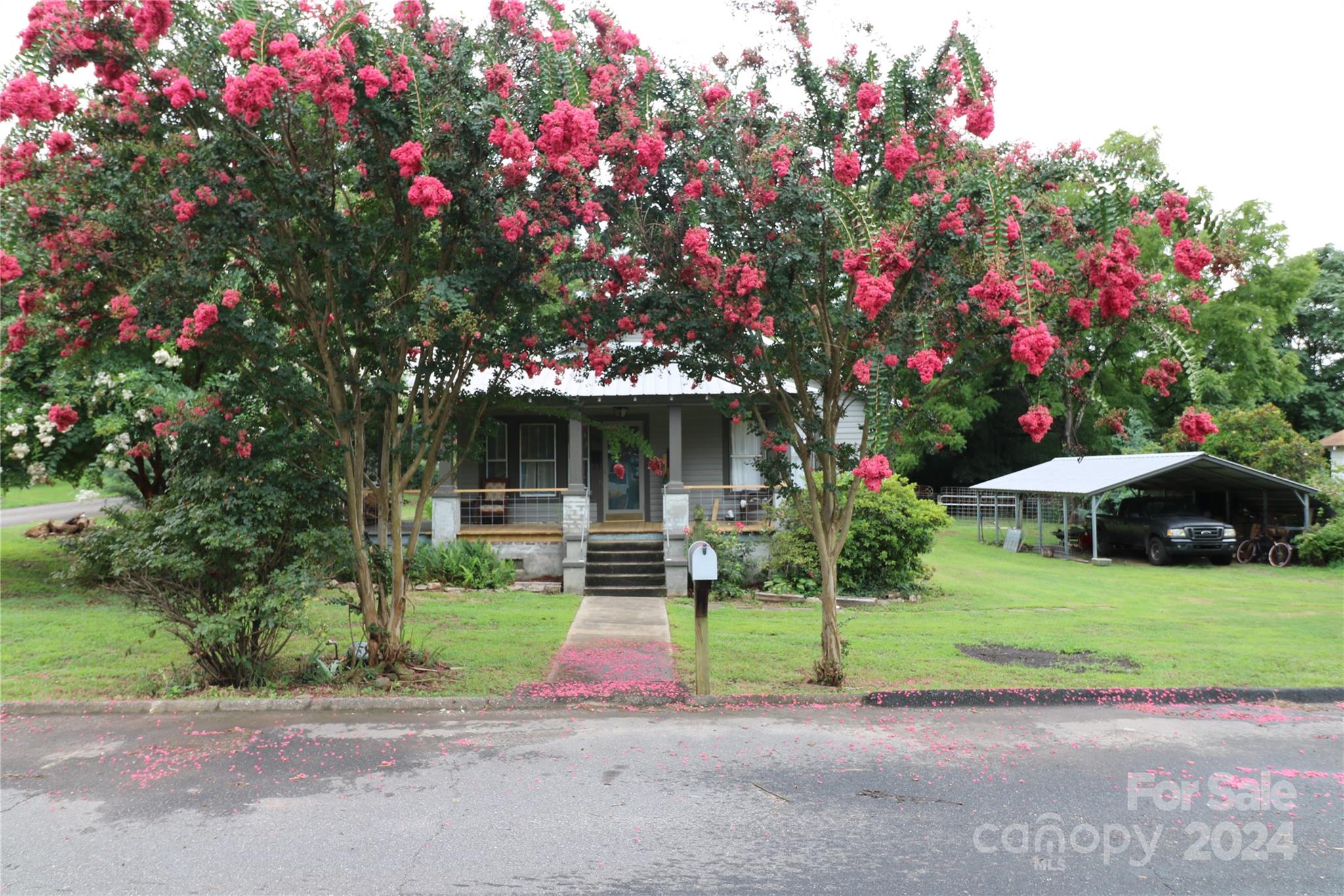 a view of a house with a big yard and large tree