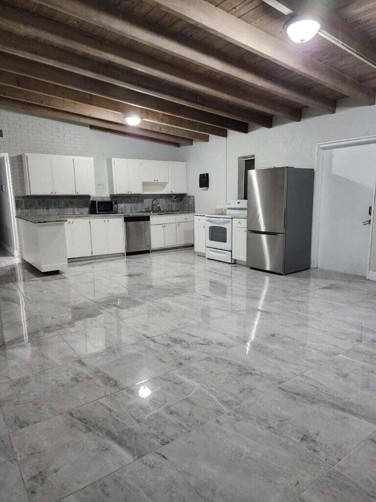 a view of a refrigerator in kitchen and an empty room