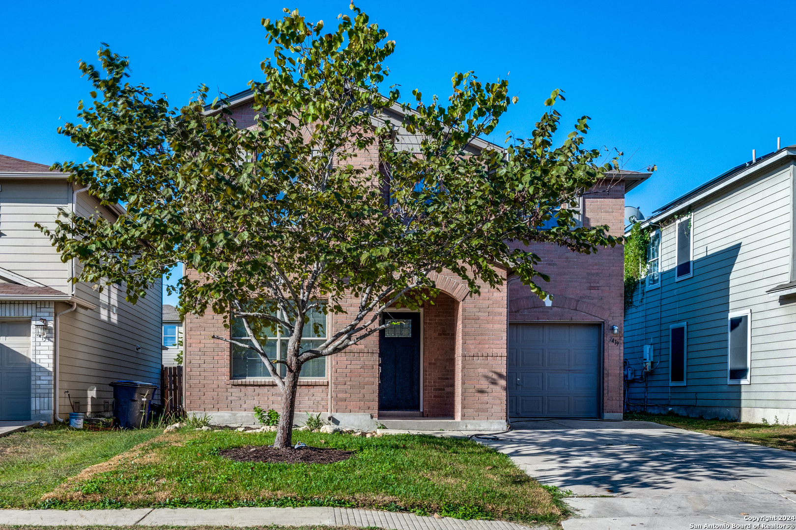 a front view of a house with a tree