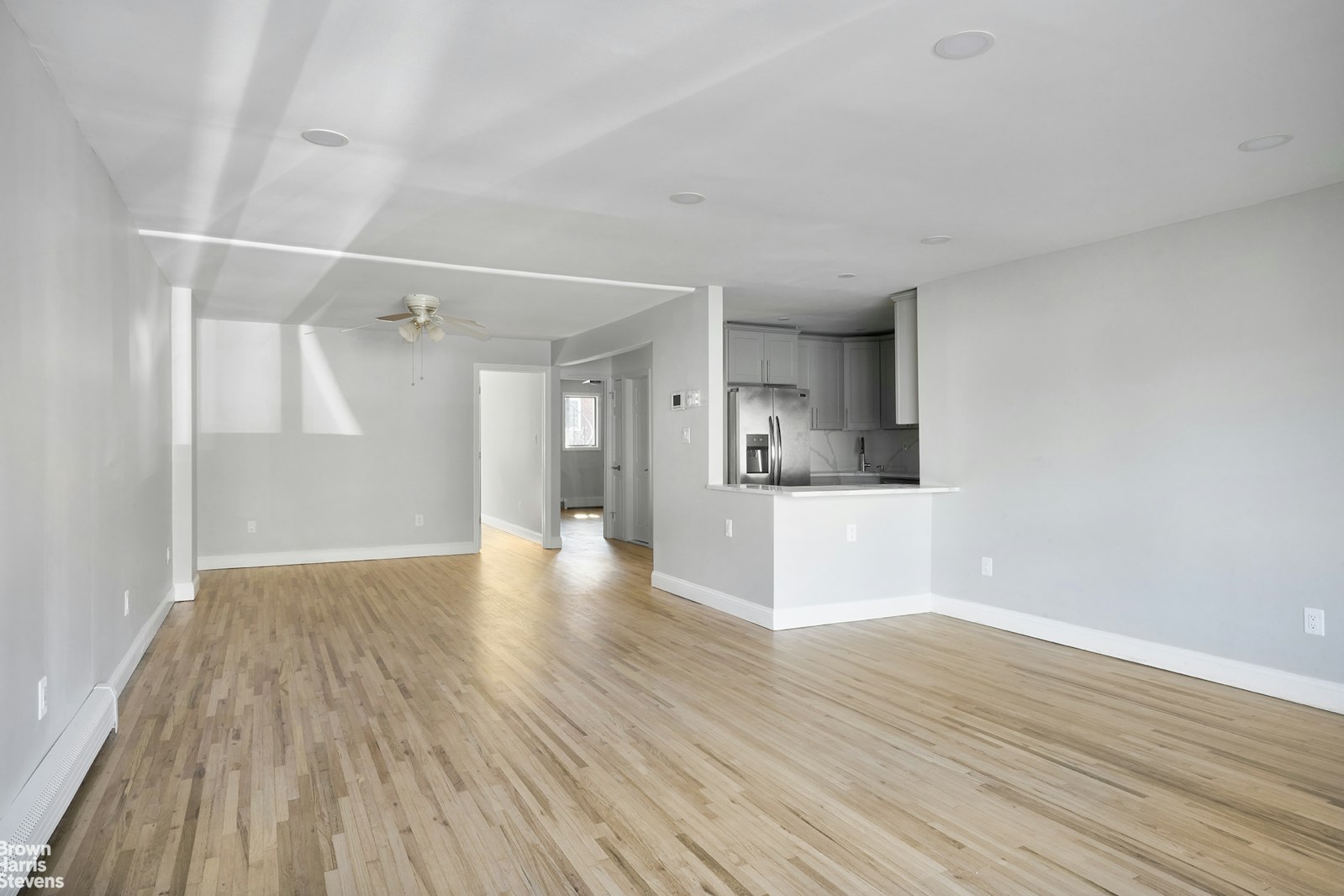 a view of a hallway with wooden floor and a bathroom