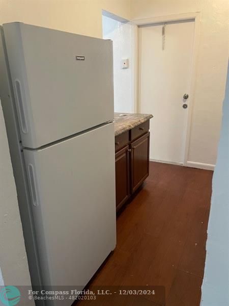 a view of a refrigerator in kitchen and an empty room