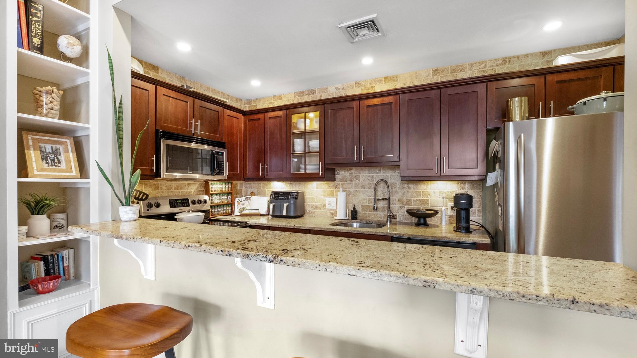 a kitchen with stainless steel appliances granite countertop a sink refrigerator and cabinets